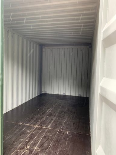 Empty shipping container with metal walls and a wooden floor.